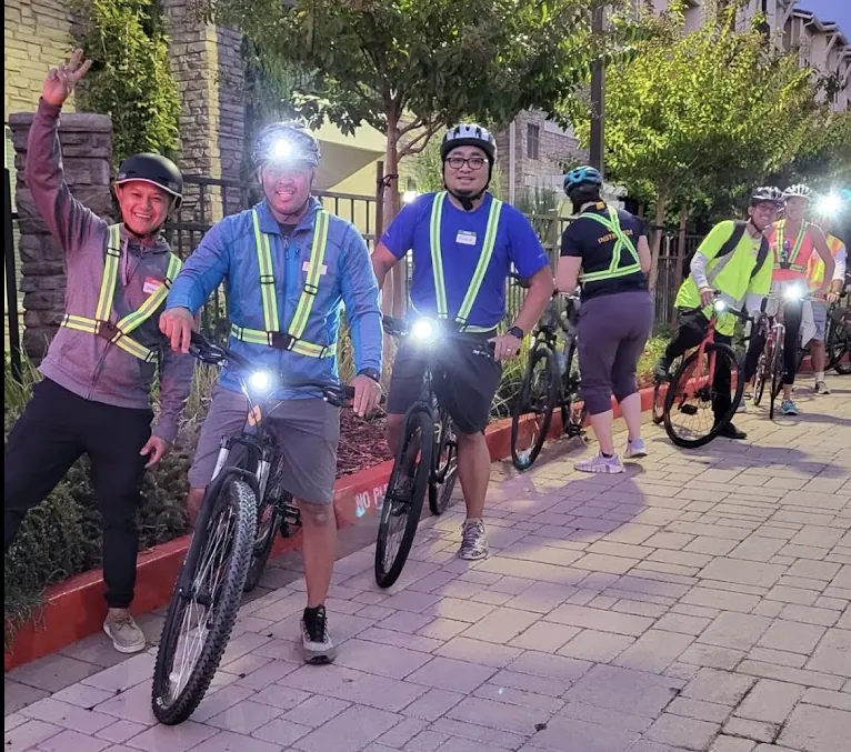 Marvin waving at the front of a line of riders in reflective vests and headlamps on an evening jibe ride
