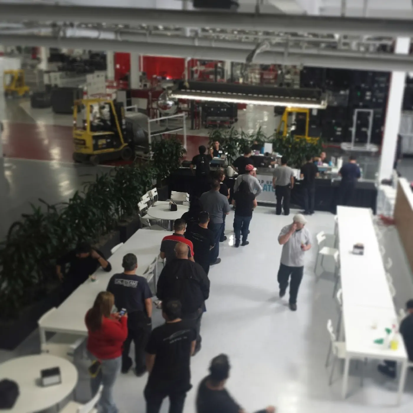A line of Tesla employees waiting for gelato inside the Fremont factory, forklifts in the background
